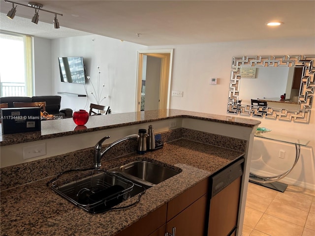 kitchen with light tile patterned floors, dishwasher, sink, and dark stone countertops