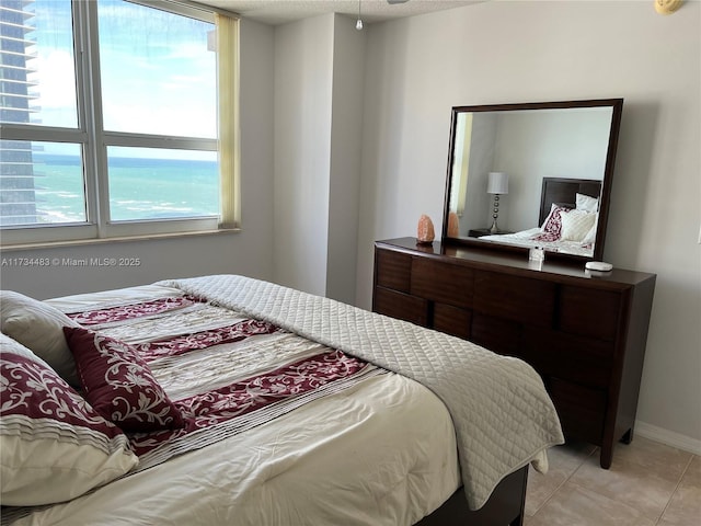 tiled bedroom featuring a water view and a textured ceiling