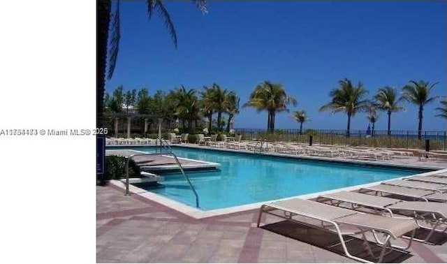 view of swimming pool with a patio and a water view