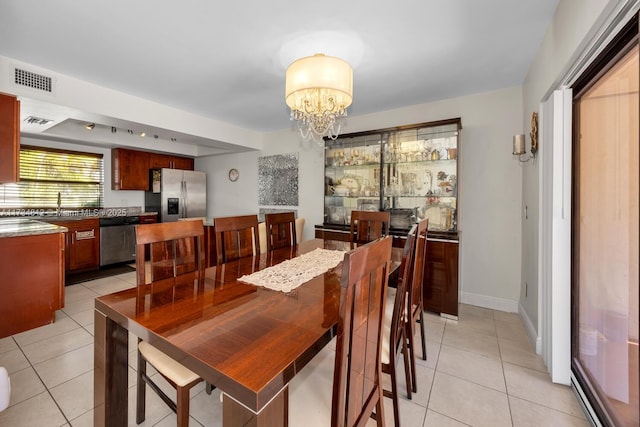 dining area with an inviting chandelier, light tile patterned flooring, and sink