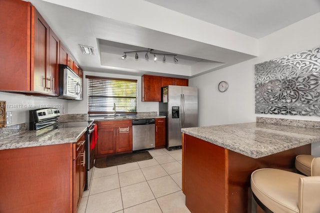 kitchen featuring a kitchen bar, a raised ceiling, kitchen peninsula, and appliances with stainless steel finishes