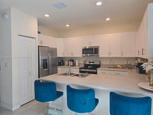 kitchen with white cabinetry, appliances with stainless steel finishes, a breakfast bar area, and light tile patterned floors