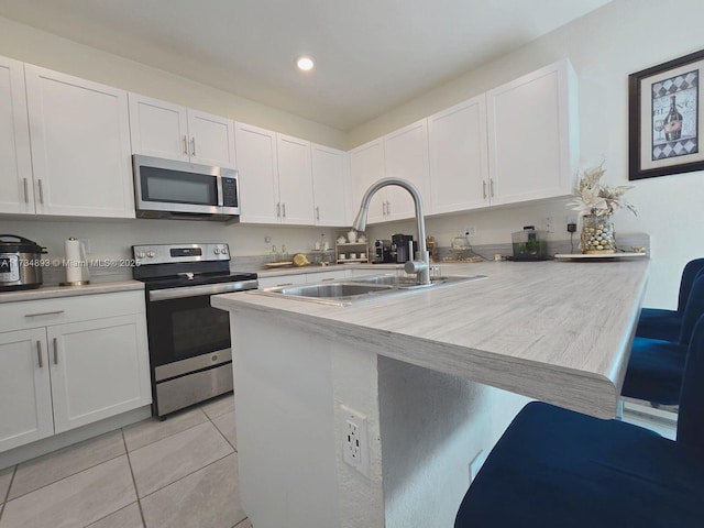 kitchen featuring light tile patterned floors, stainless steel appliances, sink, and white cabinets