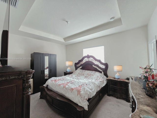 carpeted bedroom with a tray ceiling