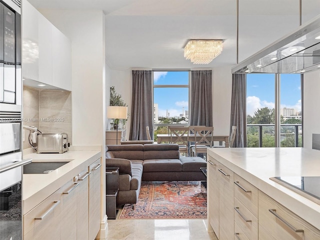 kitchen with black electric stovetop, a healthy amount of sunlight, floor to ceiling windows, and stainless steel oven