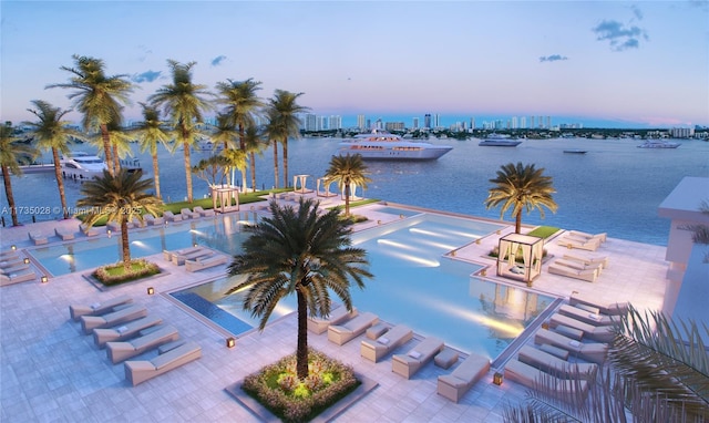 pool at dusk with a patio and a water view