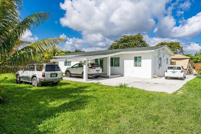 rear view of property featuring a lawn and a carport