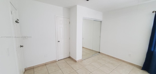 unfurnished bedroom featuring a closet and light tile patterned floors