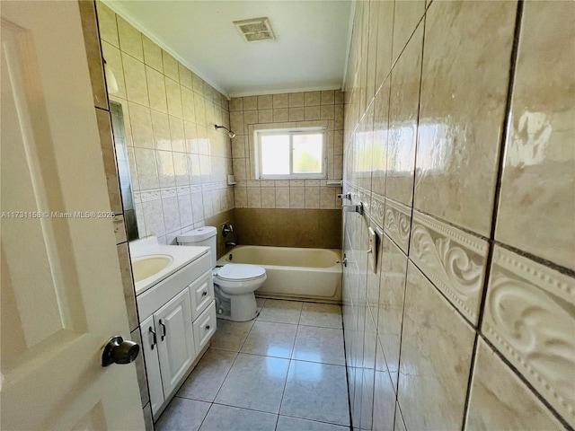 full bathroom featuring toilet, tile walls, vanity, tiled shower / bath combo, and tile patterned flooring