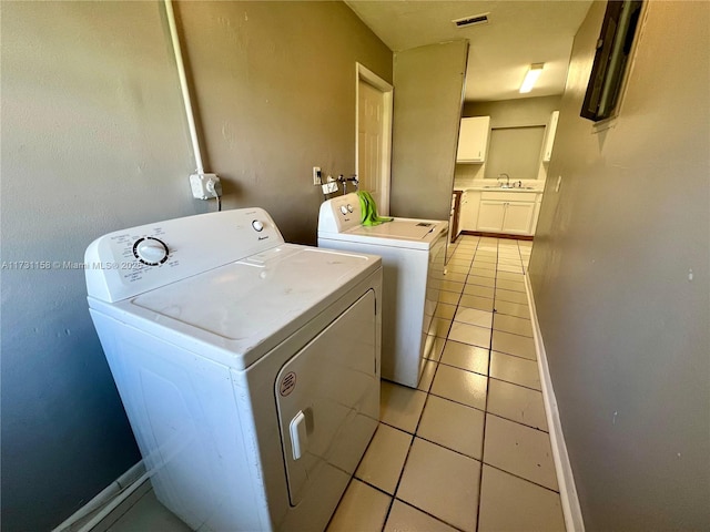 clothes washing area with separate washer and dryer, light tile patterned floors, and sink