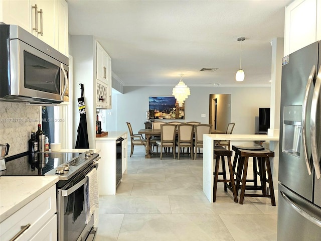 kitchen with white cabinetry, decorative backsplash, hanging light fixtures, stainless steel appliances, and crown molding