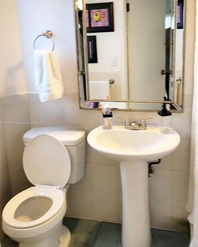 bathroom featuring tile walls, sink, and toilet