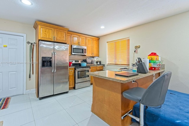 kitchen with stainless steel appliances, a breakfast bar, kitchen peninsula, and light tile patterned floors