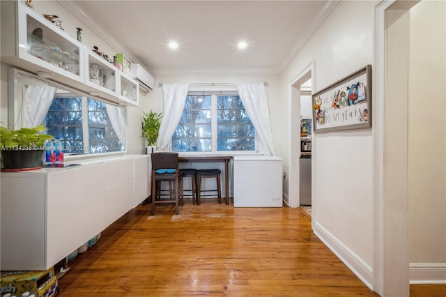 hallway with hardwood / wood-style flooring, a wall unit AC, and ornamental molding