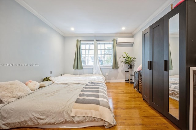 bedroom with ornamental molding, a wall mounted air conditioner, and light wood-type flooring