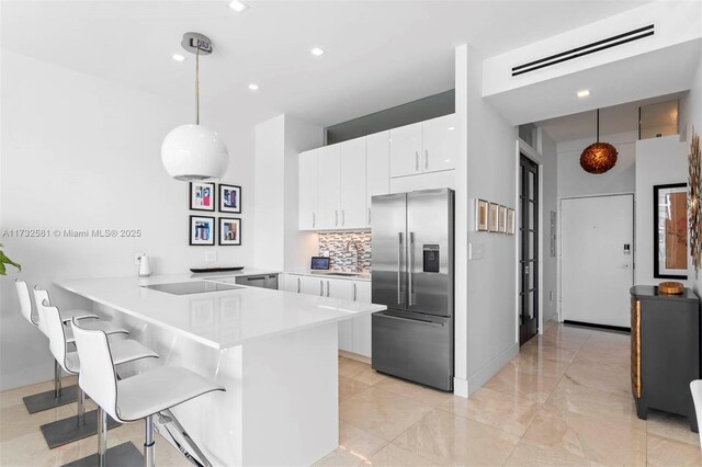 kitchen with decorative light fixtures, white cabinetry, a breakfast bar area, high end refrigerator, and kitchen peninsula