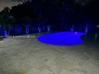 pool at night featuring a patio