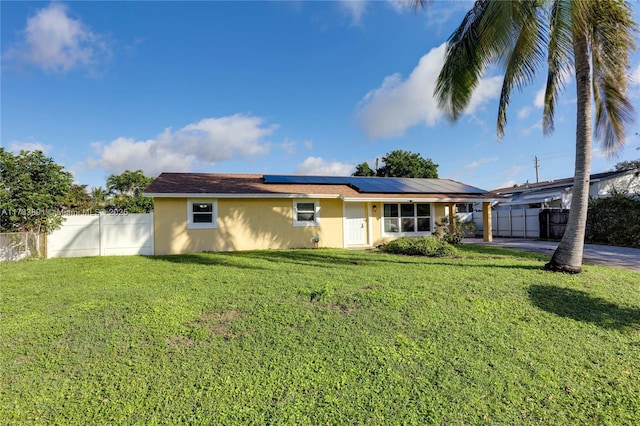 rear view of house with a lawn and solar panels