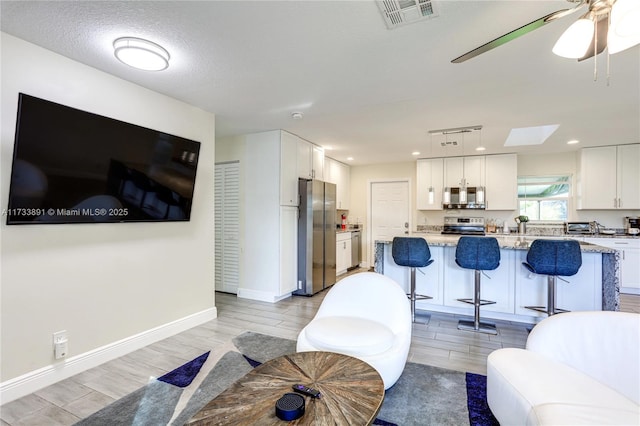 living room with ceiling fan and a textured ceiling