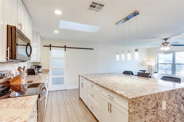 kitchen with pendant lighting, a barn door, stainless steel range with electric cooktop, and white cabinets