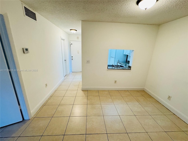 unfurnished room with light tile patterned floors and a textured ceiling