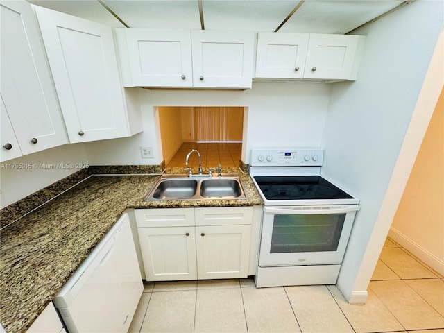 kitchen with white cabinetry, sink, dark stone countertops, light tile patterned floors, and white appliances