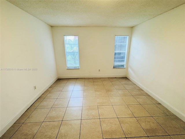 tiled empty room with a textured ceiling