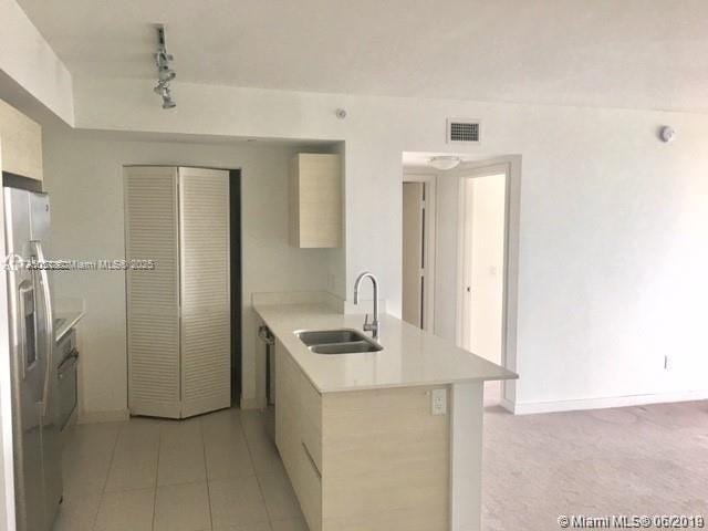 kitchen with rail lighting, sink, fridge, stainless steel dishwasher, and kitchen peninsula