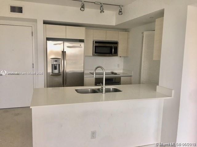 kitchen featuring stainless steel appliances, kitchen peninsula, and sink