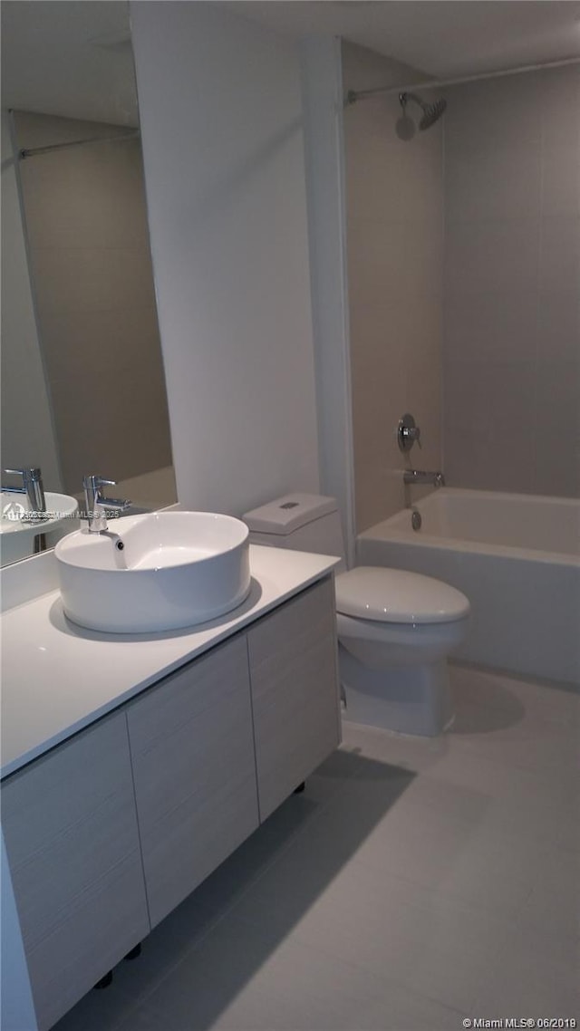 full bathroom with tiled shower / bath, vanity, toilet, and tile patterned floors