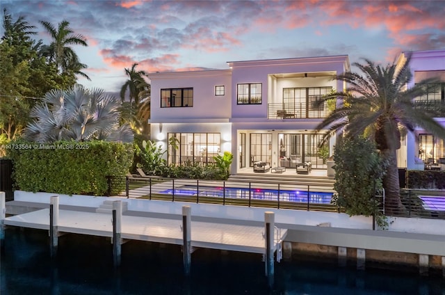 back house at dusk with a balcony and a patio area