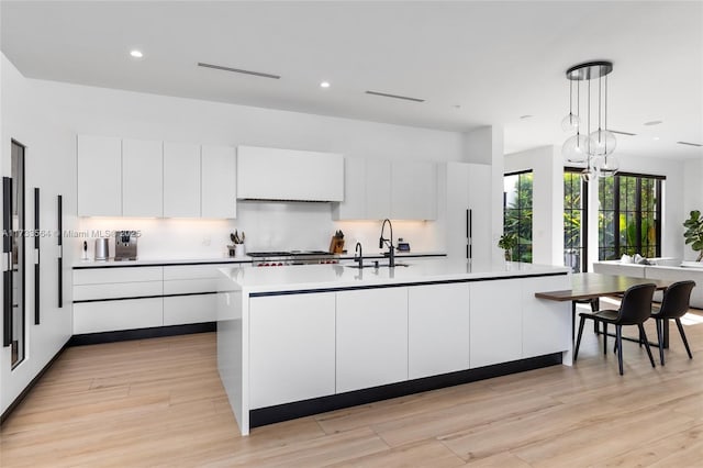 kitchen with white cabinetry, sink, an island with sink, and hanging light fixtures