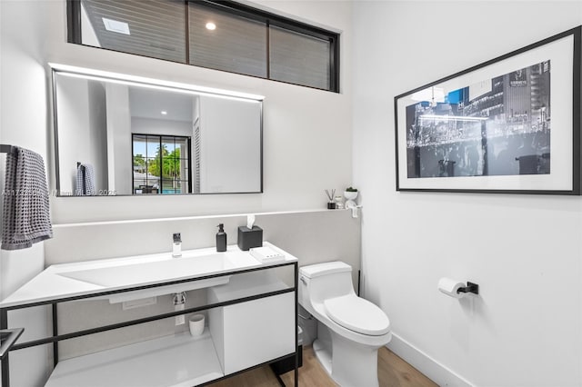 bathroom with hardwood / wood-style flooring, vanity, and toilet