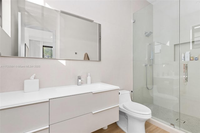 bathroom featuring tiled shower, vanity, toilet, and hardwood / wood-style floors