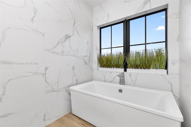 bathroom with wood-type flooring and a bath