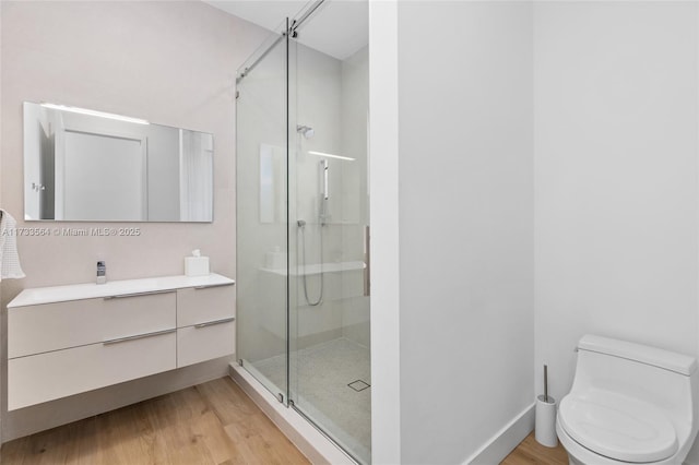 bathroom featuring a shower with door, wood-type flooring, vanity, and toilet