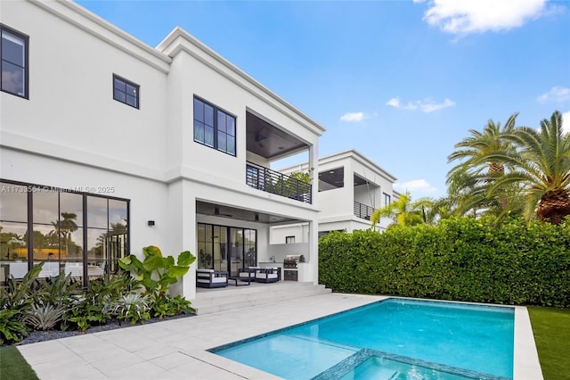 back of property featuring a fenced in pool, a patio, a balcony, ceiling fan, and an outdoor living space