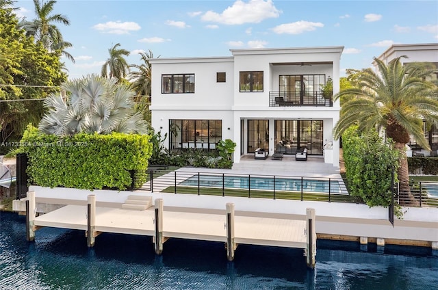 back of property with a patio area, a balcony, and a water view