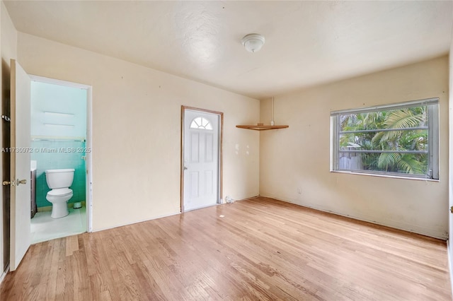 unfurnished bedroom with ensuite bathroom and light hardwood / wood-style floors