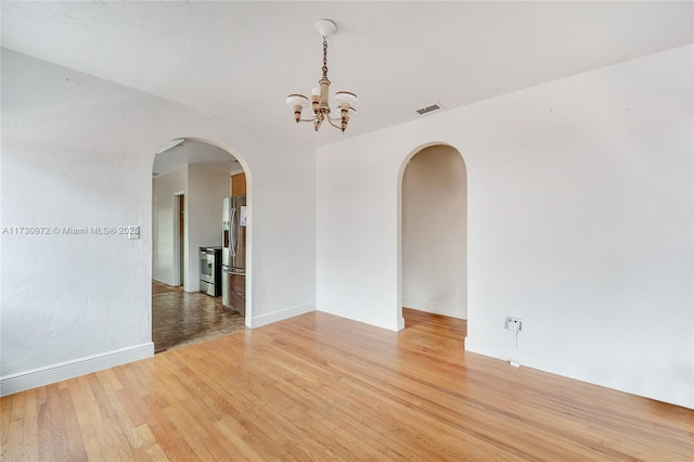 spare room with hardwood / wood-style floors and a notable chandelier