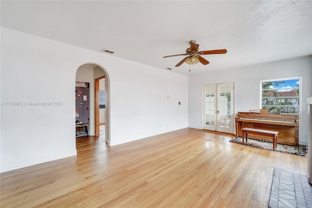 unfurnished living room with french doors, ceiling fan, and light hardwood / wood-style flooring