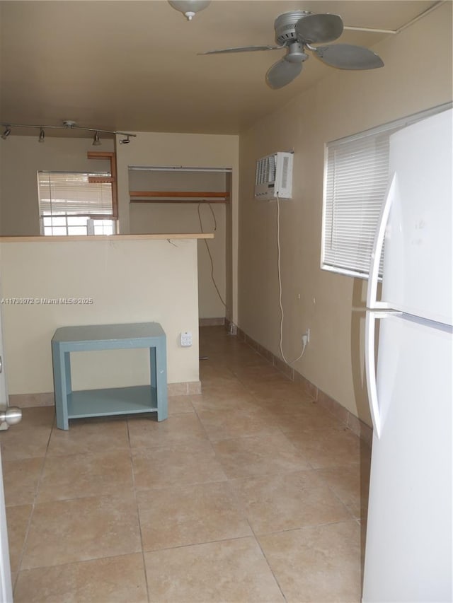 kitchen with white refrigerator, light tile patterned flooring, an AC wall unit, and ceiling fan