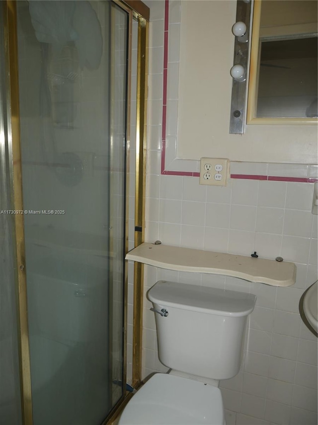 bathroom with tile walls, a shower with door, and toilet