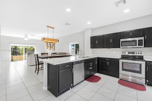 kitchen with sink, hanging light fixtures, light tile patterned floors, kitchen peninsula, and stainless steel appliances