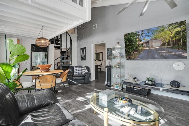 living room featuring visible vents, dark wood-style floors, ceiling fan, stairway, and a high ceiling