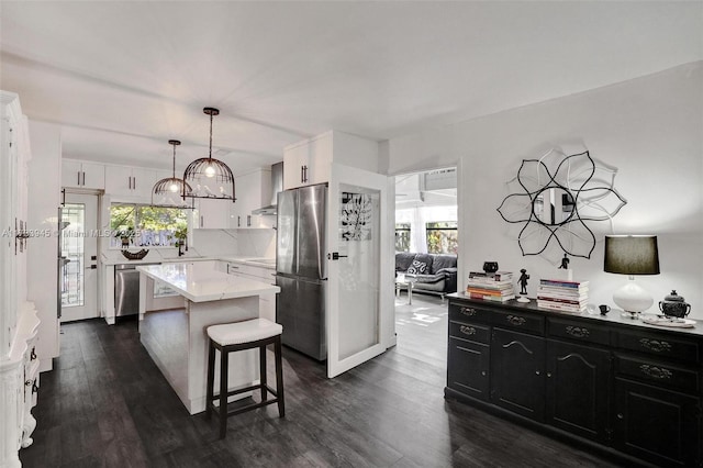 kitchen featuring light countertops, appliances with stainless steel finishes, dark wood-type flooring, a kitchen island, and dark cabinetry