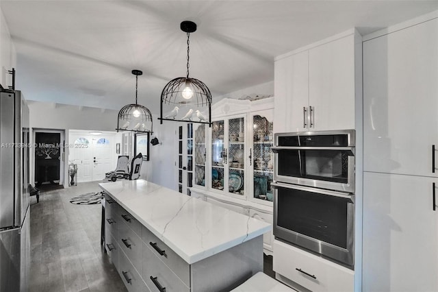 kitchen featuring hanging light fixtures, appliances with stainless steel finishes, a kitchen island, and white cabinetry