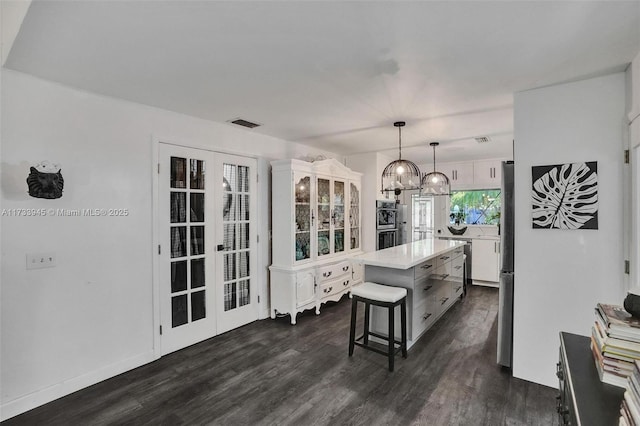 kitchen with hanging light fixtures, a kitchen island, white cabinetry, and light countertops