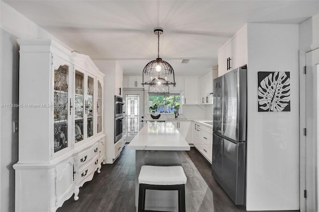 kitchen with glass insert cabinets, stainless steel appliances, white cabinets, light countertops, and decorative light fixtures