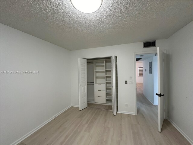 unfurnished bedroom featuring a textured ceiling, a closet, and light wood-type flooring